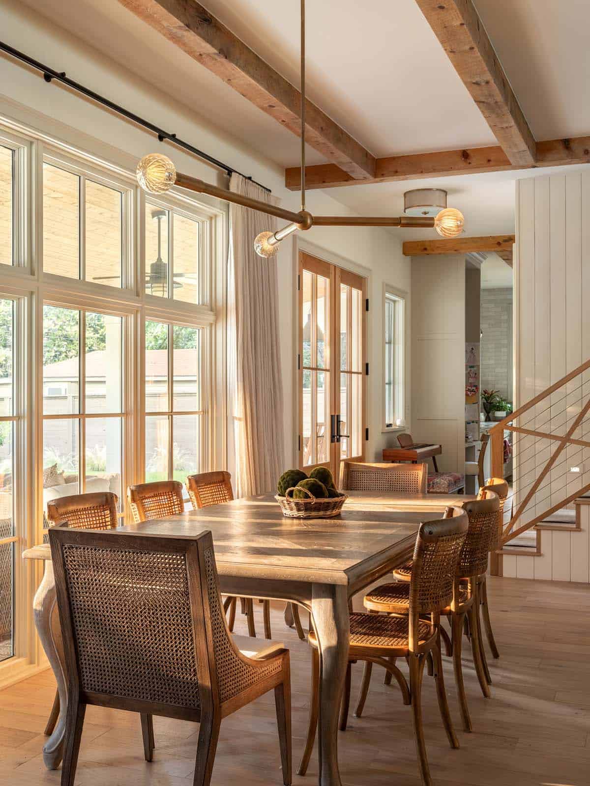 Dining room with cane chairs beneath brass branching pendant light