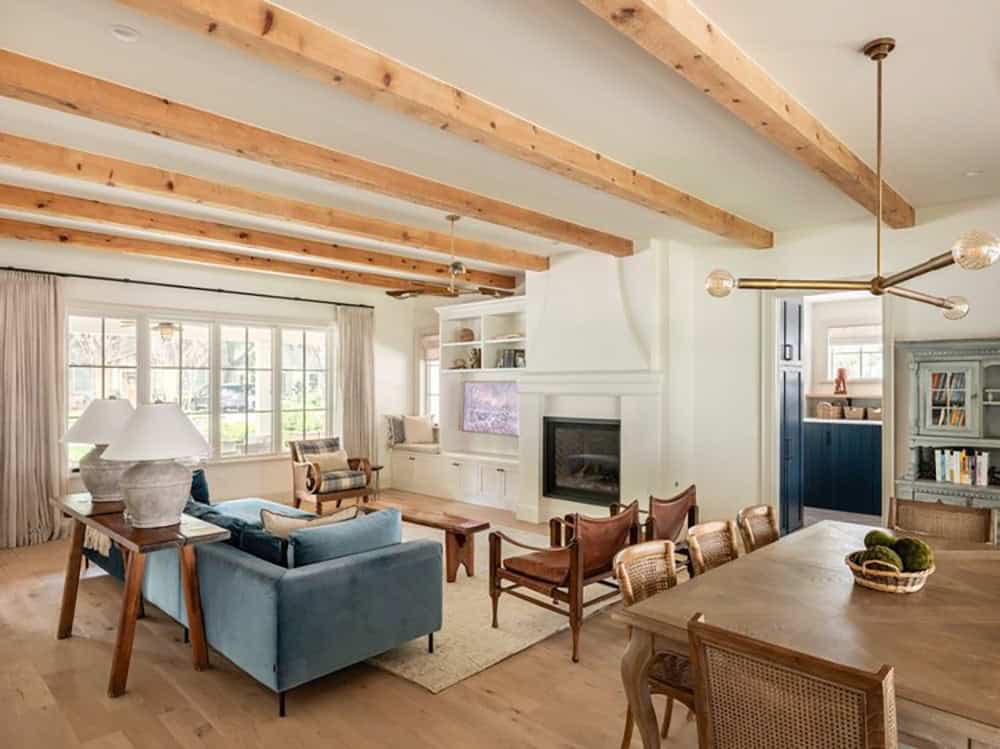 Open living and dining area with beamed ceiling and fireplace