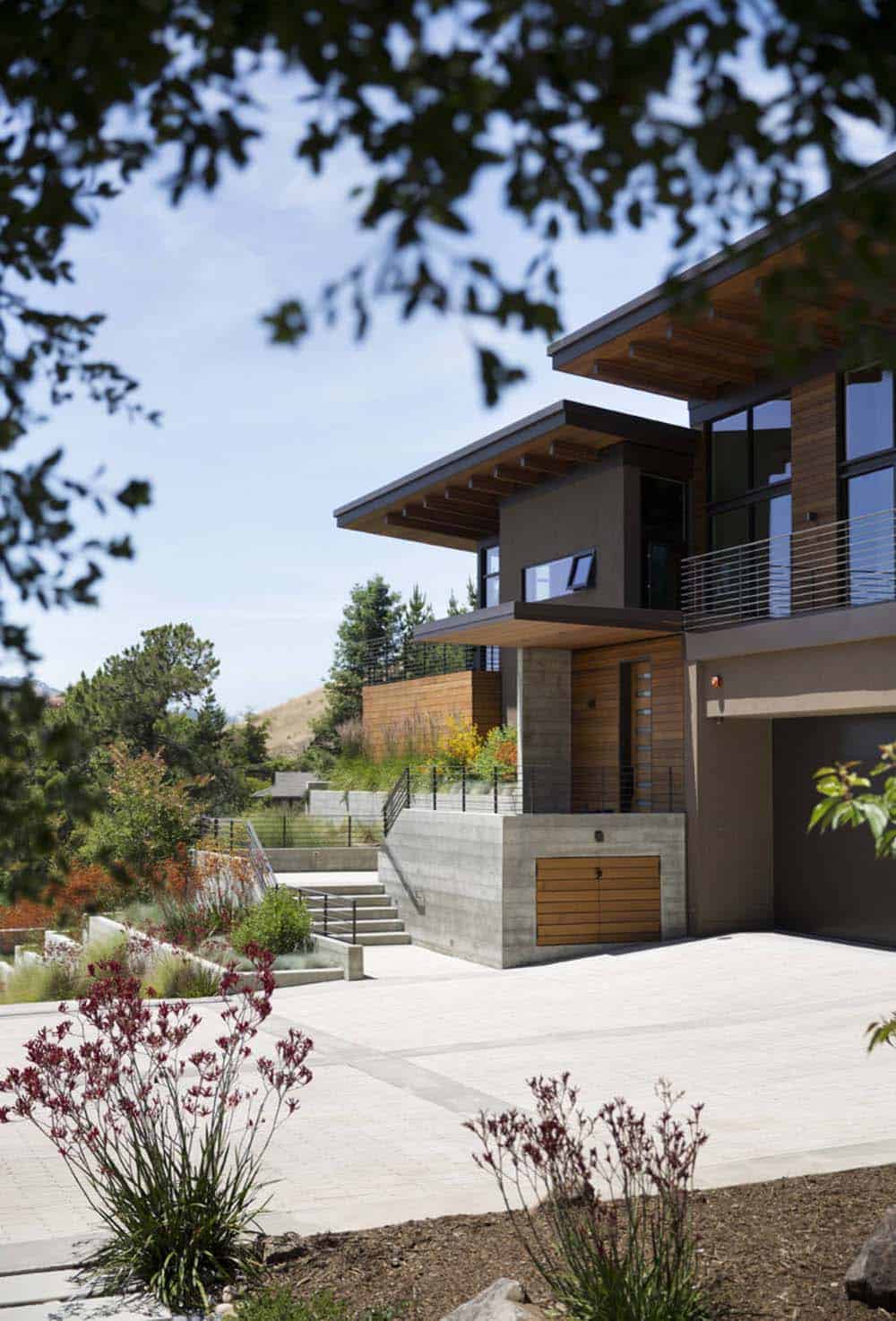Cantilevered wood roofline shades entry with concrete retaining walls and driveway