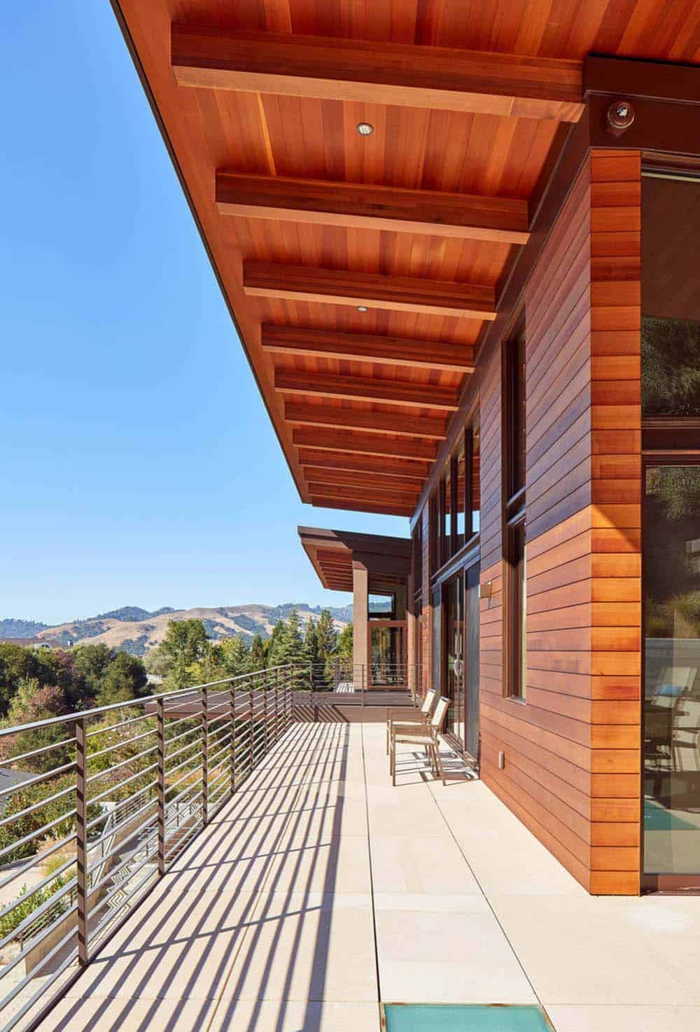 Covered deck with cedar ceiling beams overlooks hillside and distant mountain views