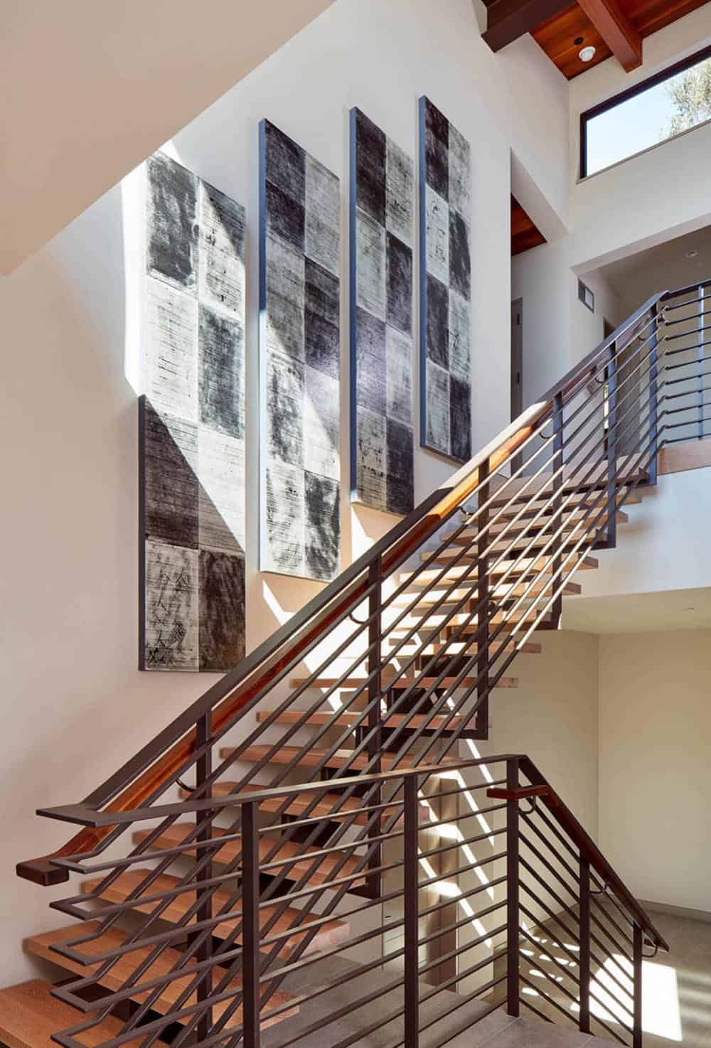 Floating wood staircase with metal railings beneath abstract art installation