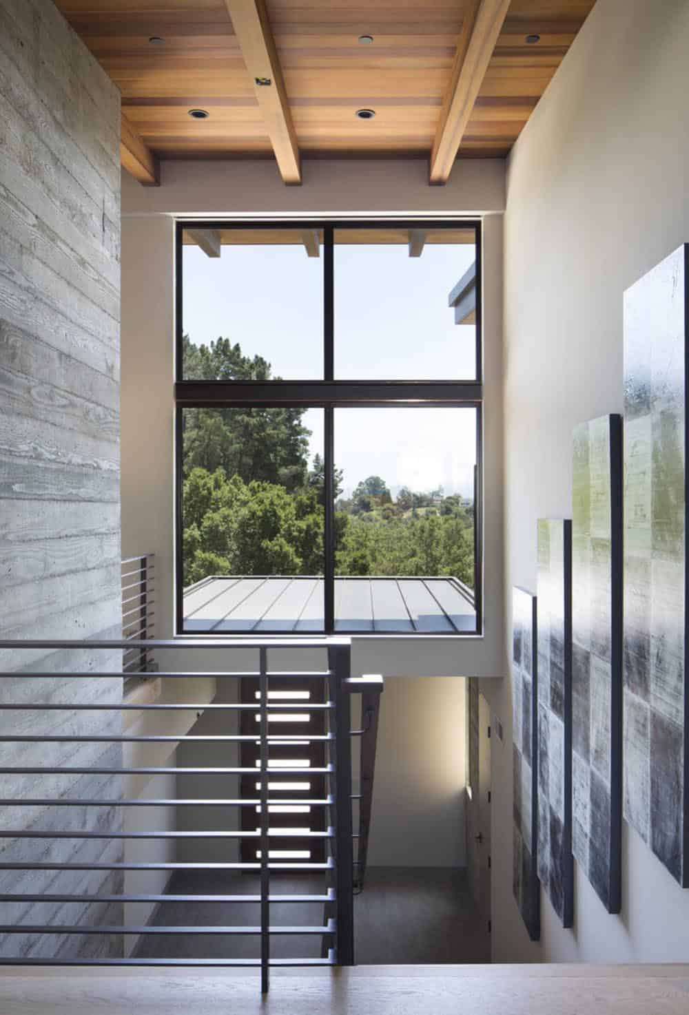 Stairwell landing features tall picture window framed by concrete and cedar ceiling