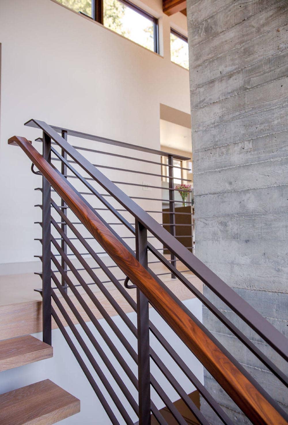 Close-up of wood handrail against board-formed concrete column on staircase