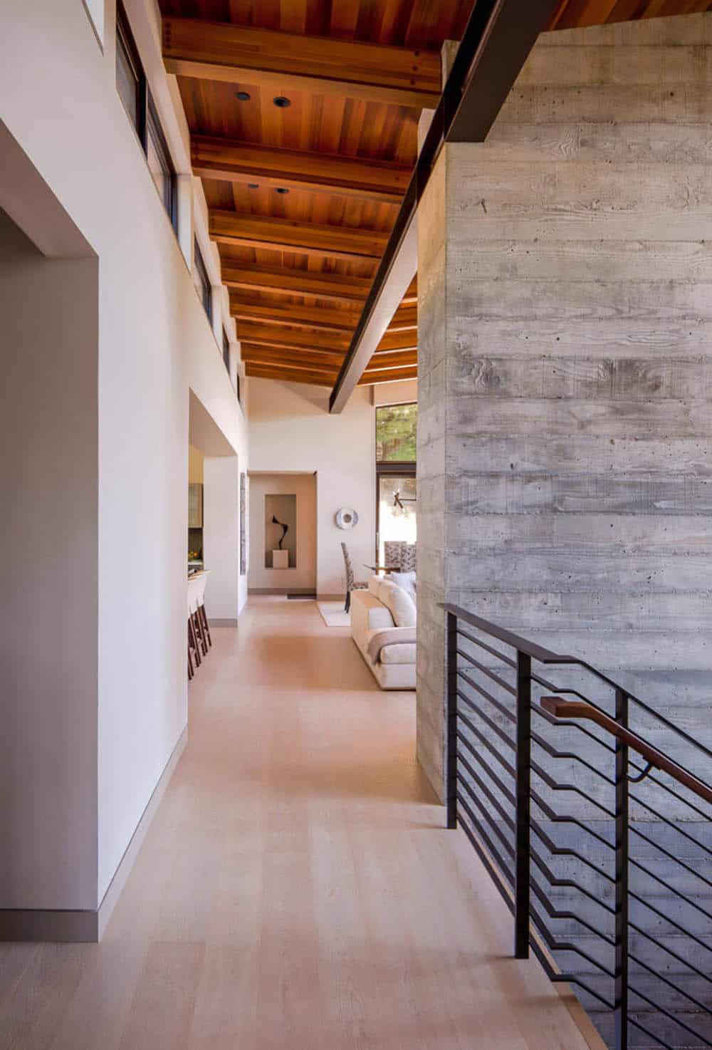 Hallway view toward living room framed by concrete wall and cedar ceiling