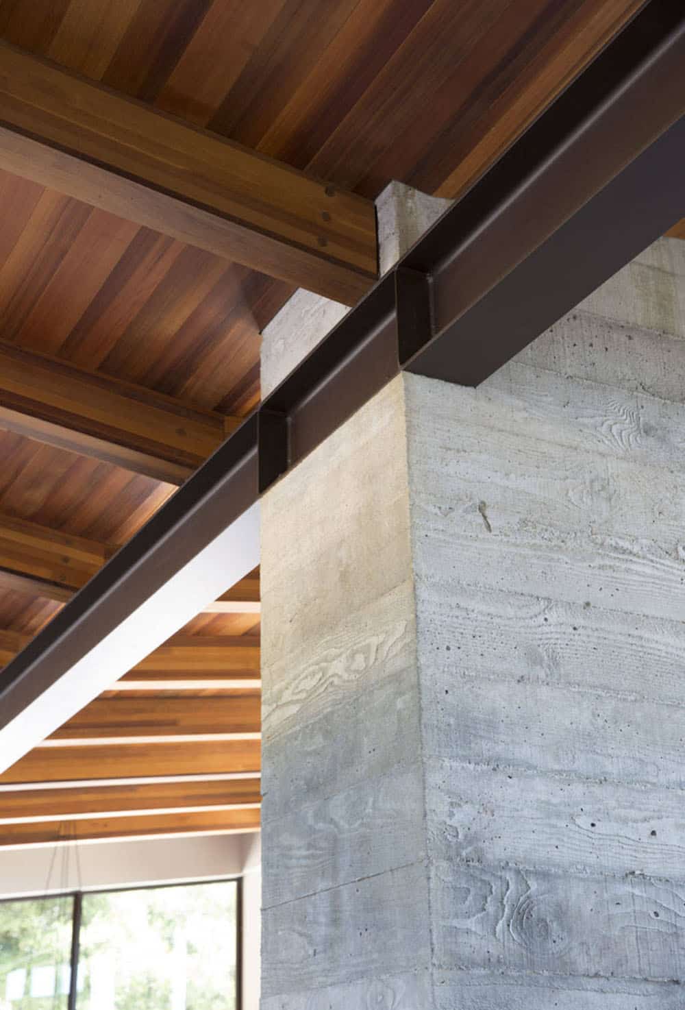 Detail of steel beam connection meeting board-formed concrete column and cedar ceiling
