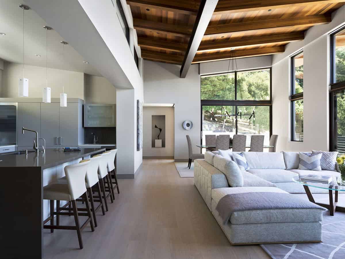 Open-concept living and dining area beneath vaulted cedar beam ceiling