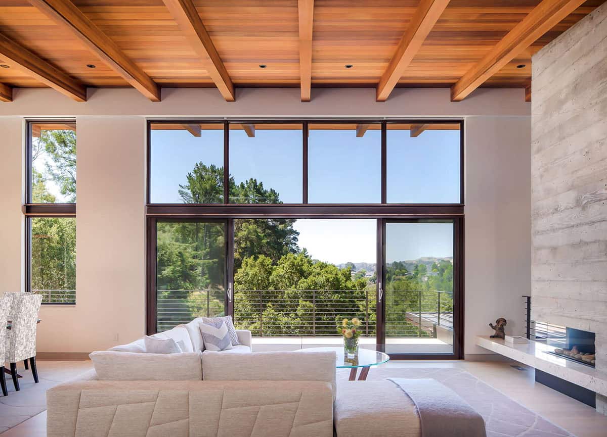 Living room with floor-to-ceiling windows framing concrete fireplace and tree canopy