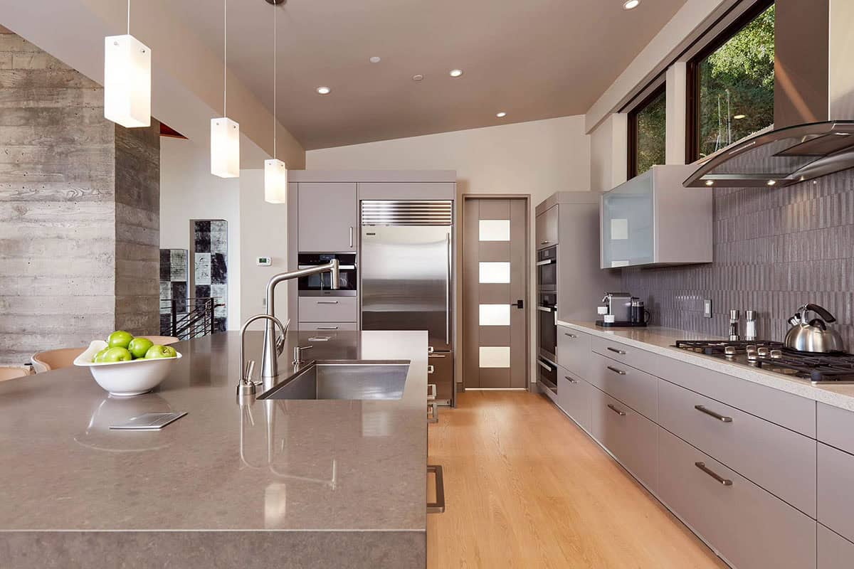 Galley kitchen with stainless appliances, gray cabinetry, and light wood flooring