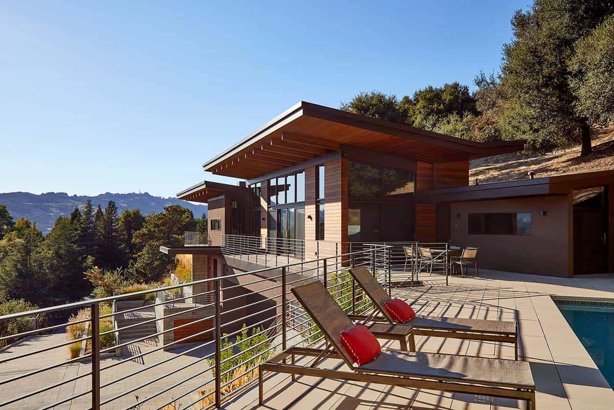 Exterior view of home's cantilevered roofline with pool deck and hillside backdrop