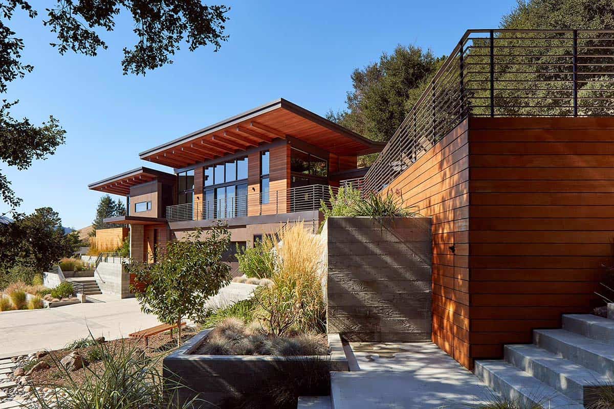 Angular home exterior with cedar cladding rises above terraced retaining walls