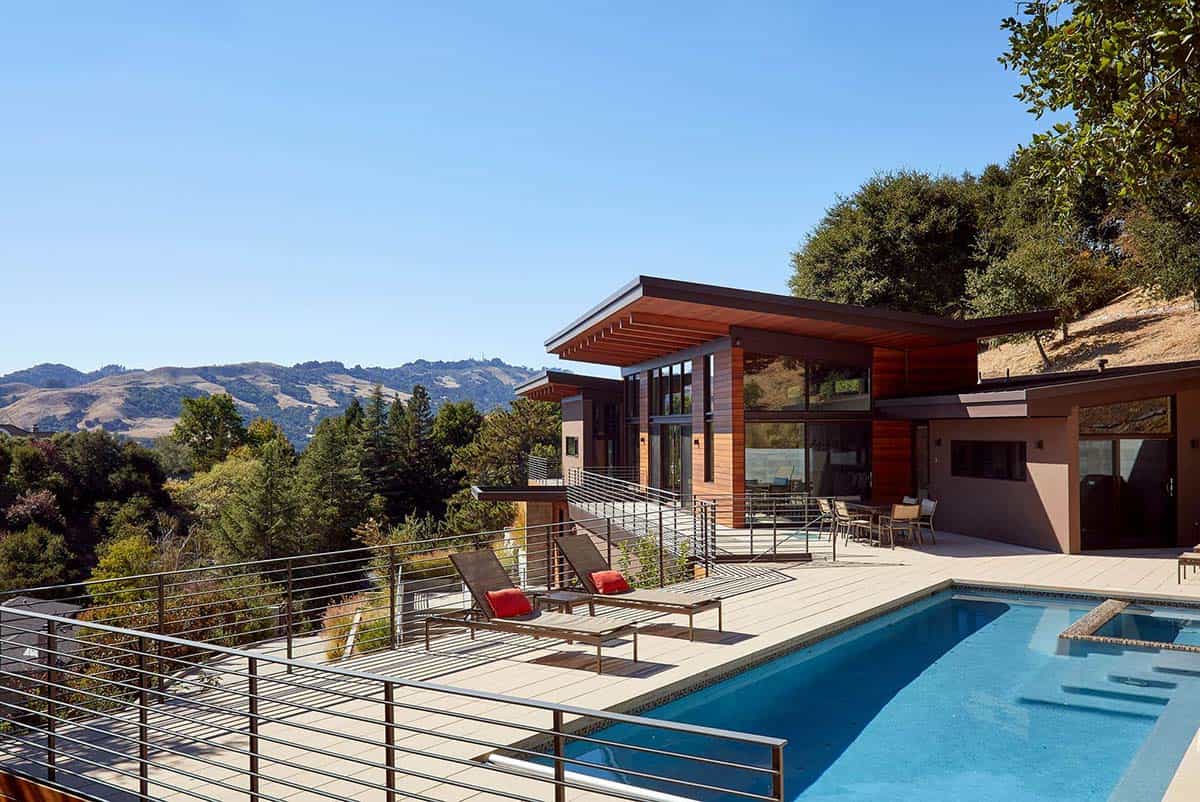 Backyard pool deck overlooks wooded canyon with layered mountain views beyond