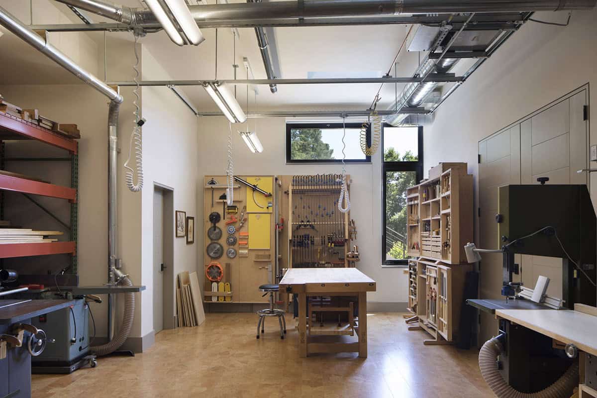Woodworking shop features built-in tool storage, workbench, and cork flooring