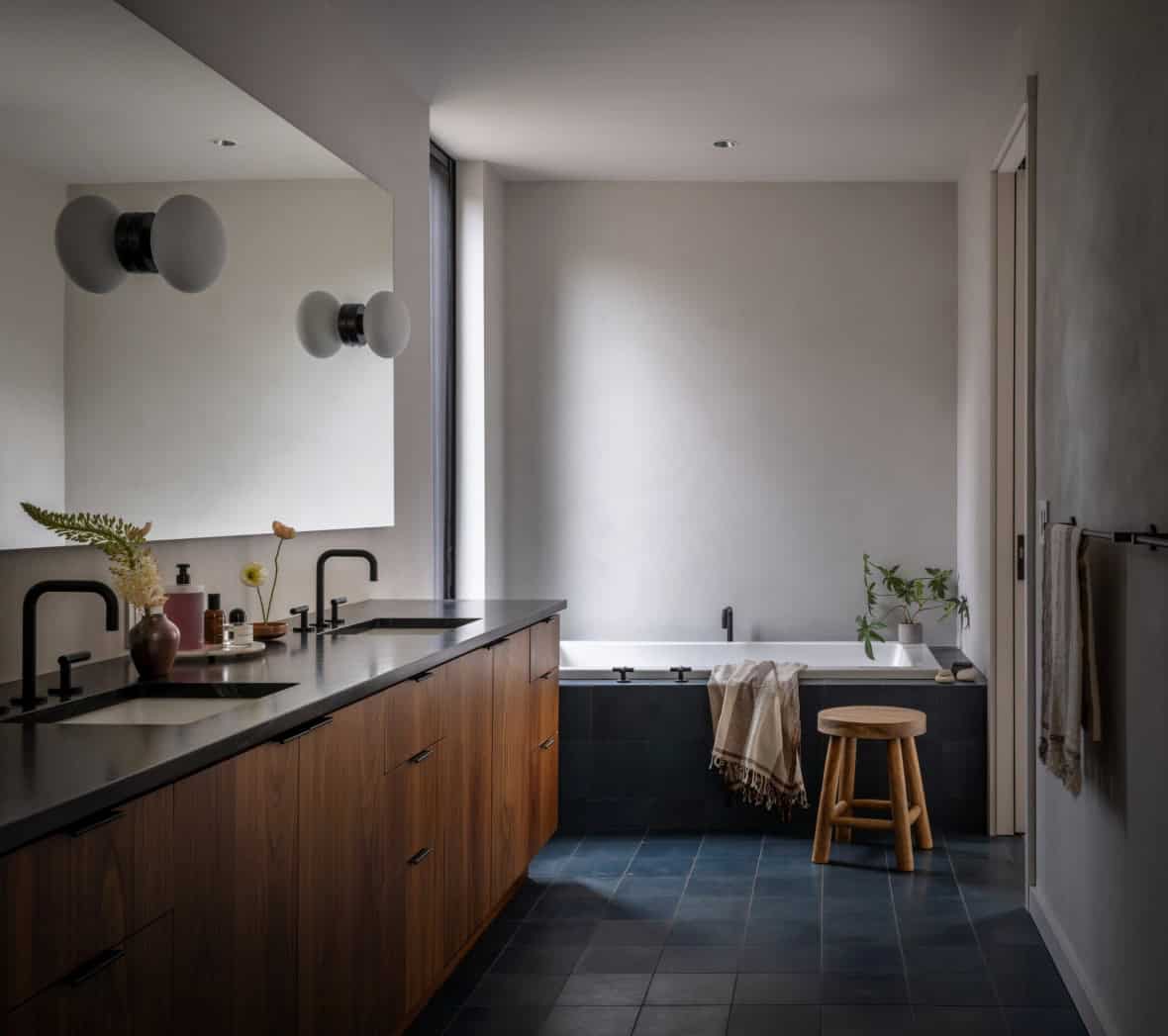 Primary bathroom with walnut double vanity, black fixtures, and blue tile floor