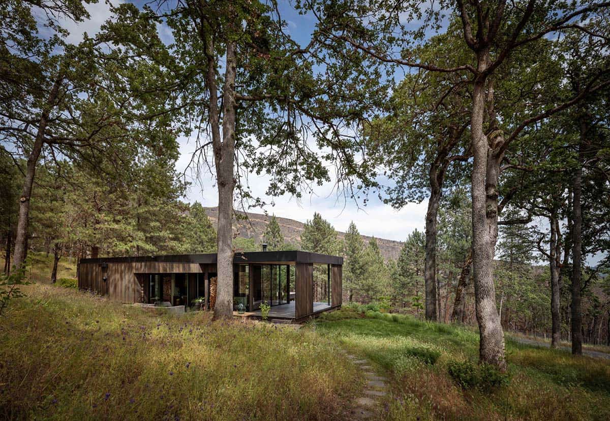Modern home surrounded by oak trees with rocky cliffs rising beyond