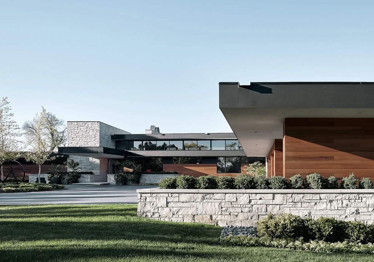 Cantilevered wood facade with stone retaining wall and driveway