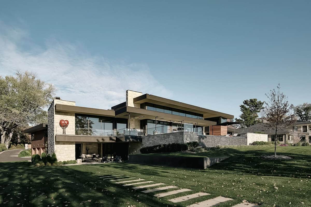 Two-story lake house facade with layered stone and glass
