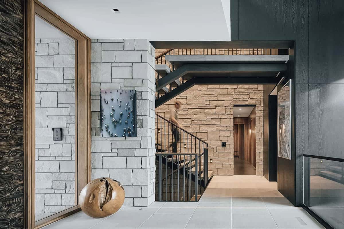 Stone entry hall with floating steel staircase and wood sphere sculpture