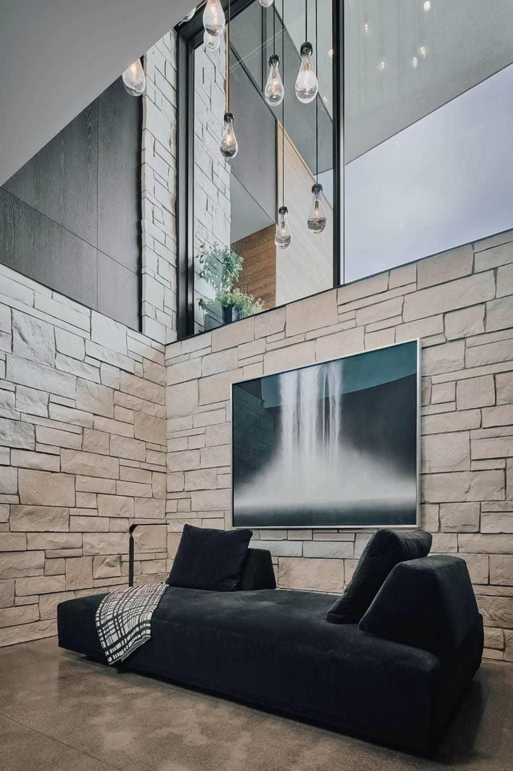 Stone stairwell nook with black chaise beneath a waterfall painting