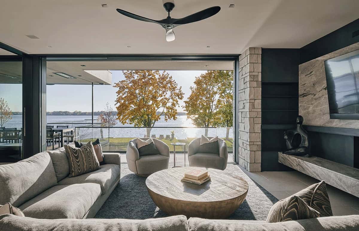 Screened porch seating facing the lake through autumn trees