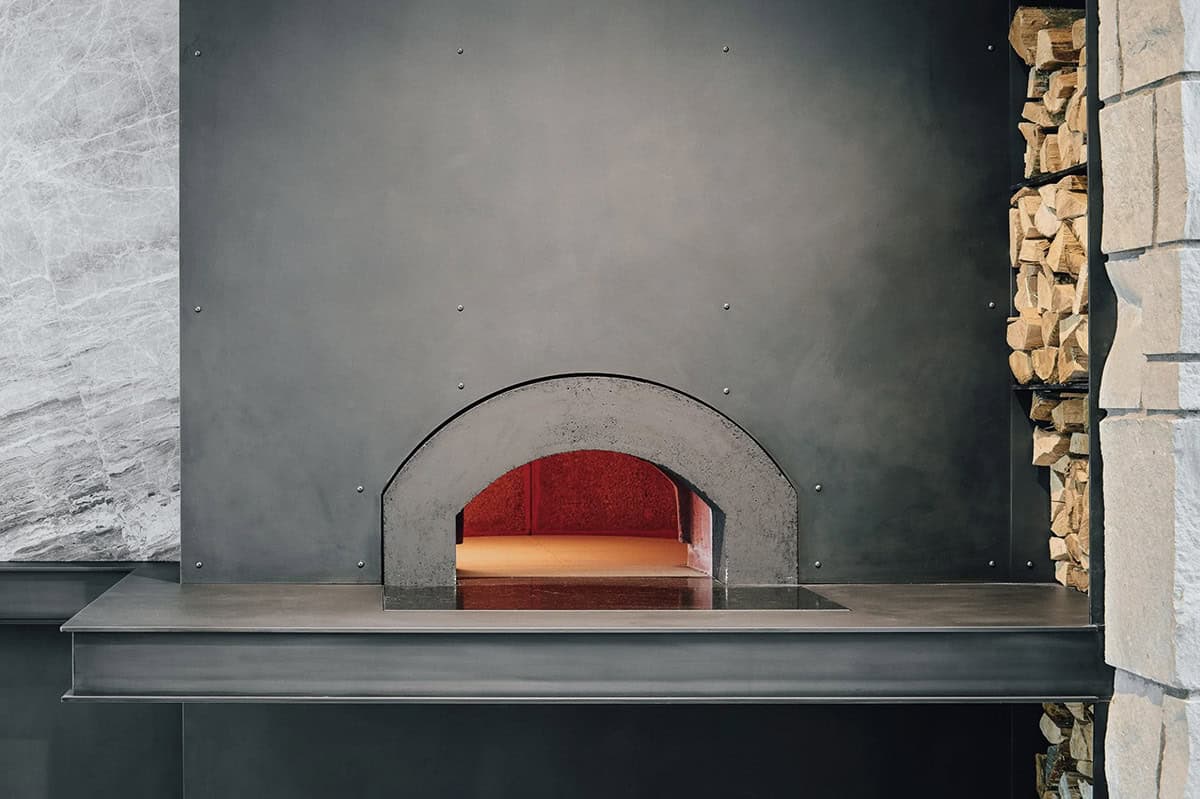 Built in wood fired pizza oven with stacked firewood storage
