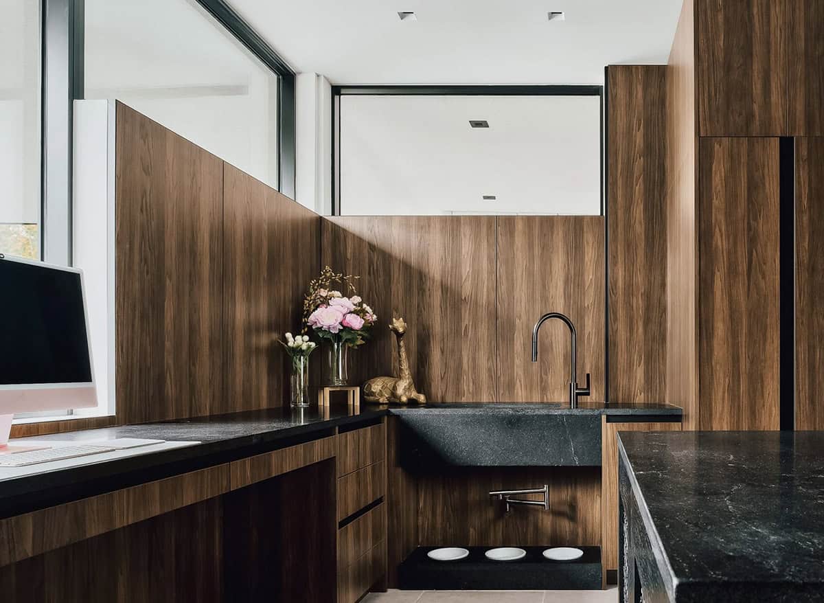 Wood paneled wet bar with black stone farmhouse sink