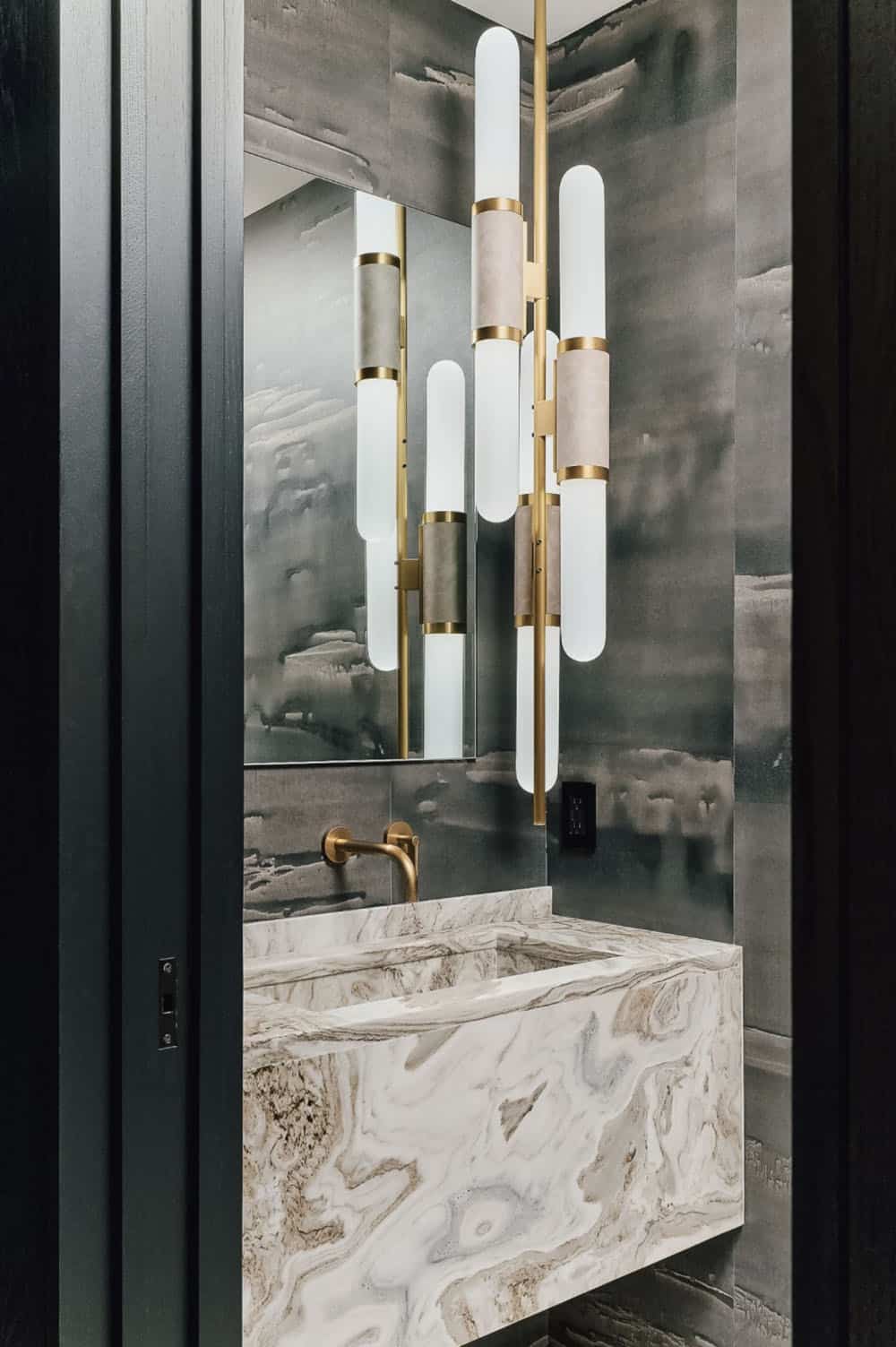 Powder room with marble vanity and brass tube wall sconce