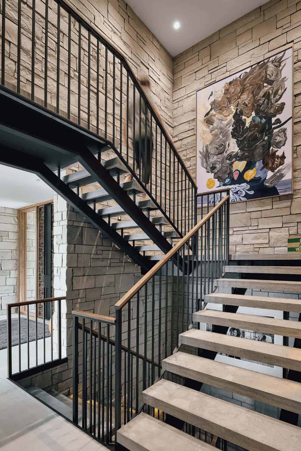 Stone stairwell with abstract painting and black metal railing