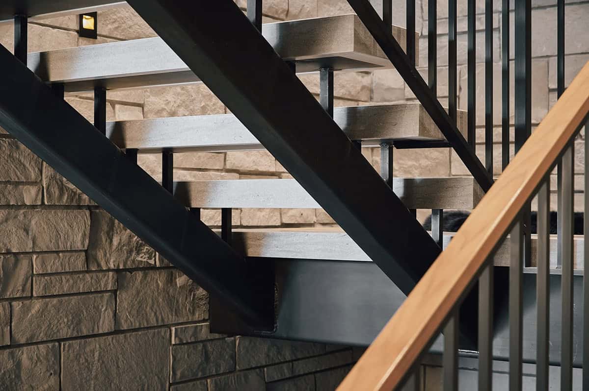 Detail of floating stone treads on a black steel stair stringer