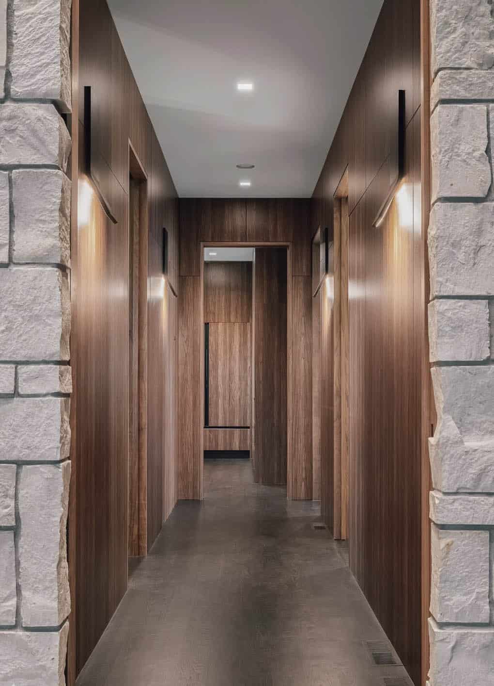 Walnut paneled hallway leading to guest bedroom with sconces