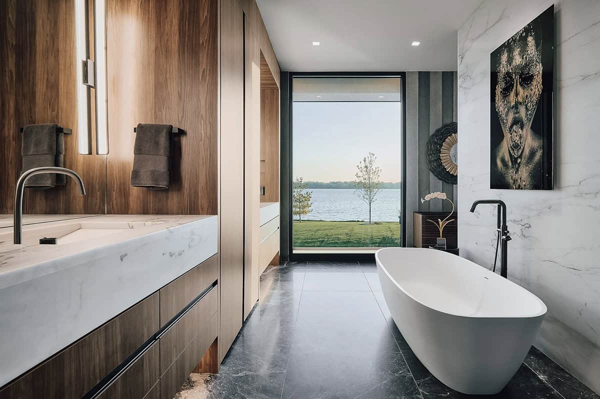 Primary bathroom with freestanding tub framed by a window to the lake