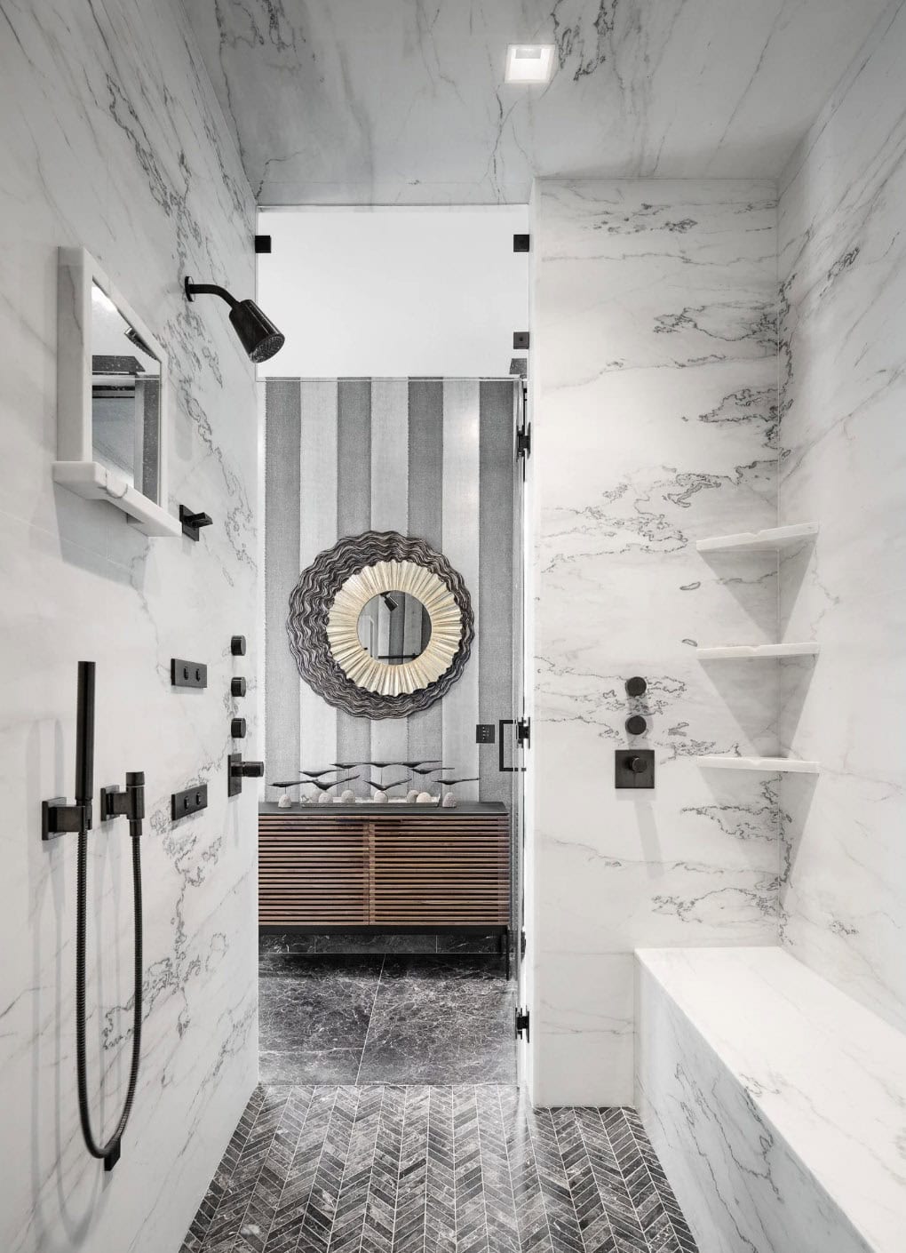 Marble shower with striped wallpaper and black fixtures beyond