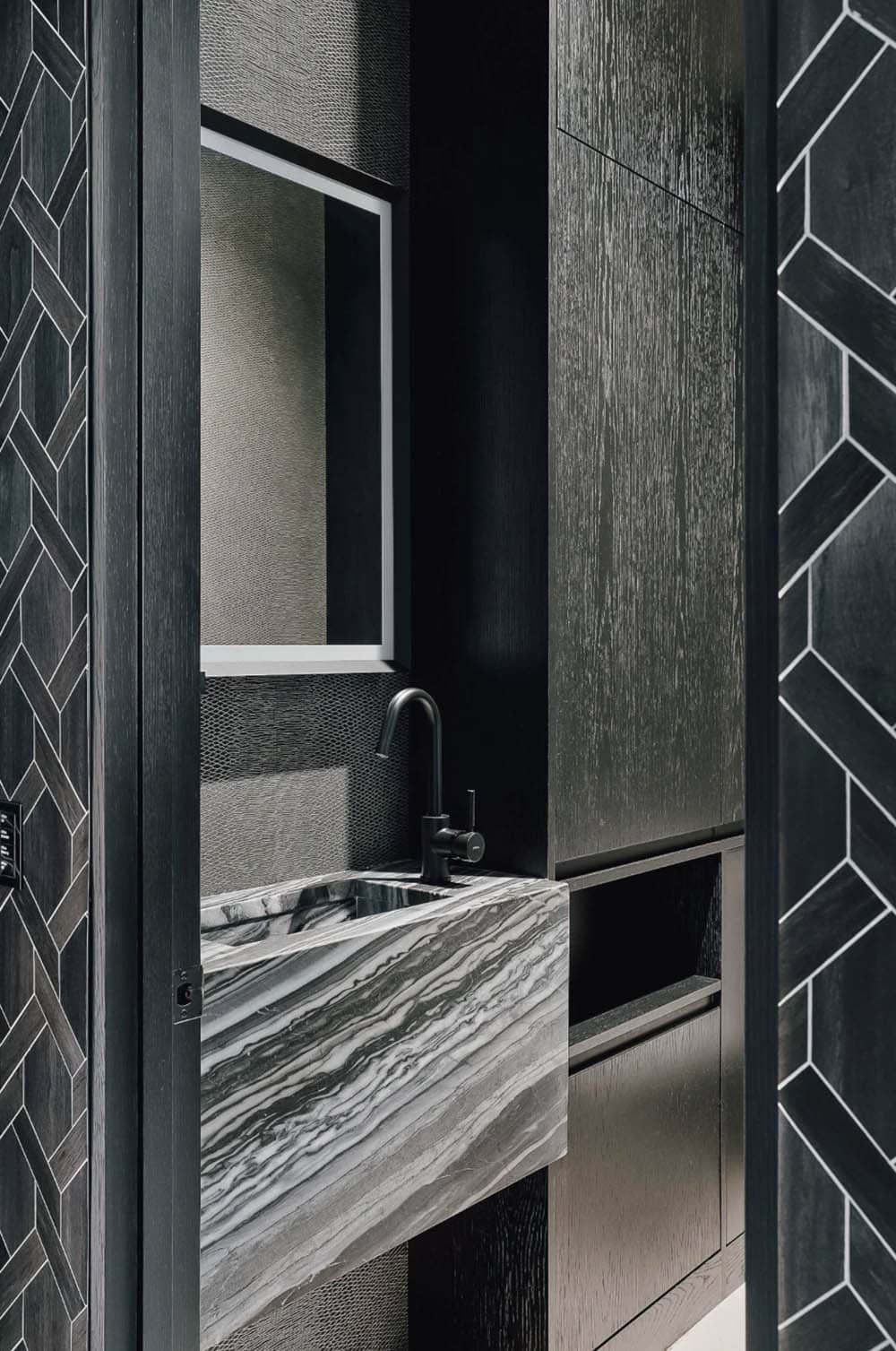 Dark wood powder room with black fixtures and geometric tile