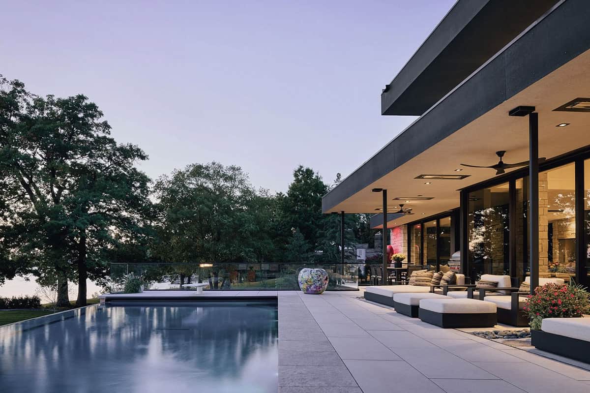 Twilight view of the pool deck and glass railing along the lake