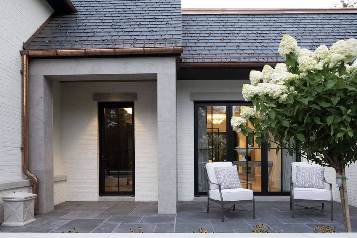 Covered breezeway connecting stone archway to glass paneled doors
