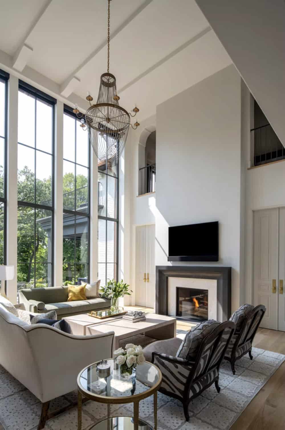 Vaulted great room with wire chandelier and gas fireplace lit