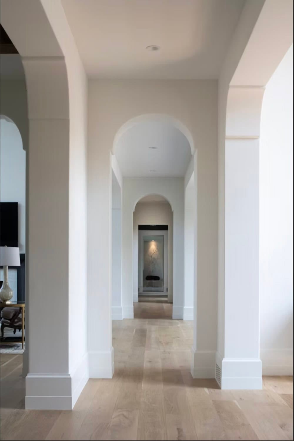 Arched hallway leading toward a sculptural art niche beyond