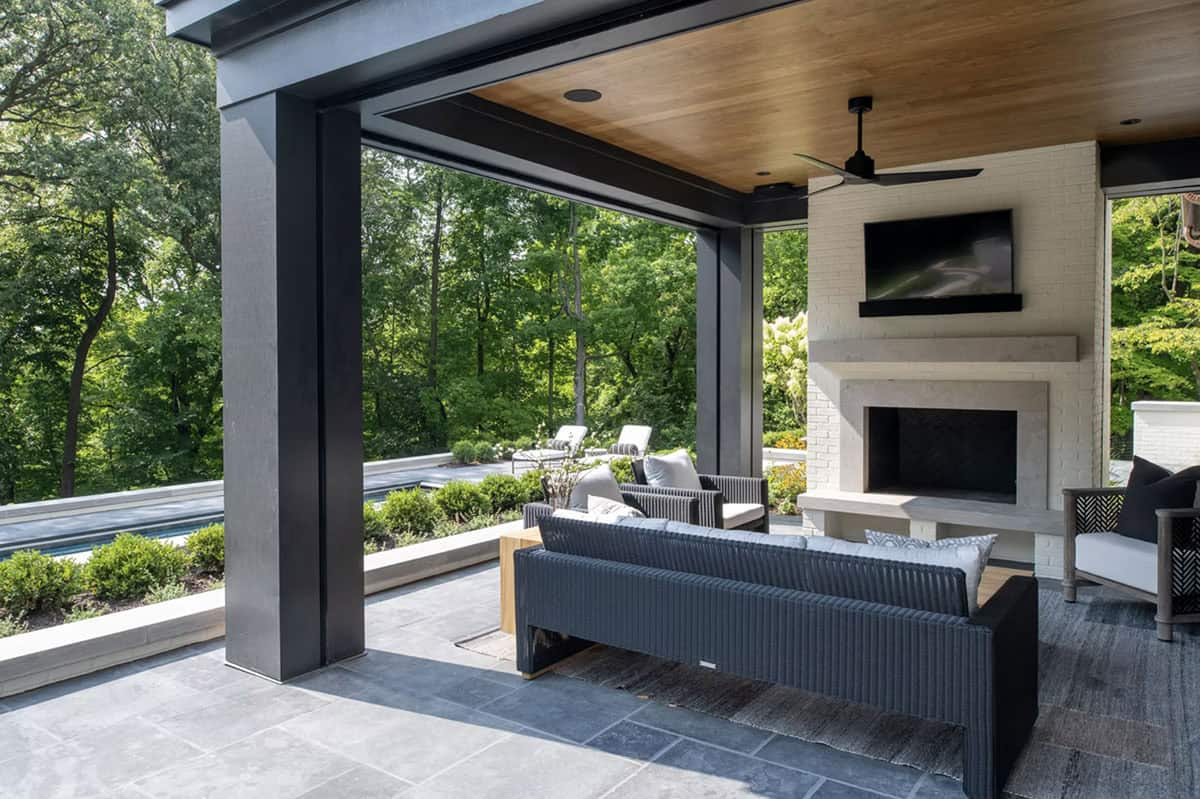 Covered patio lounge framed by black steel beams and pool