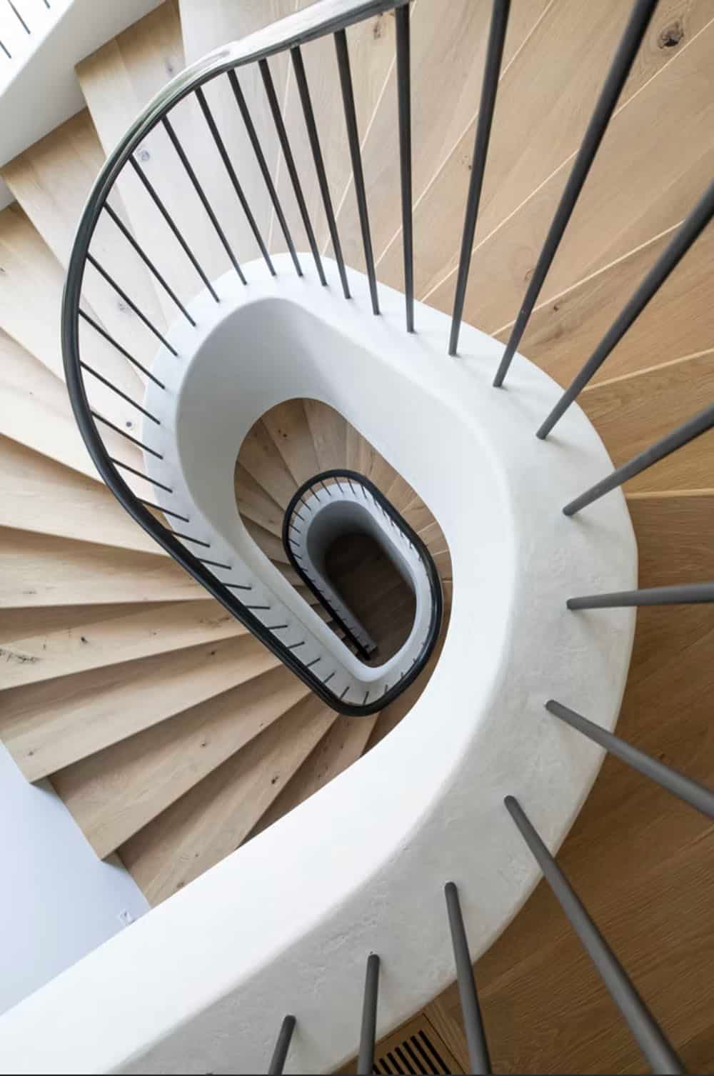 Overhead view of curved white staircase with slender iron balusters