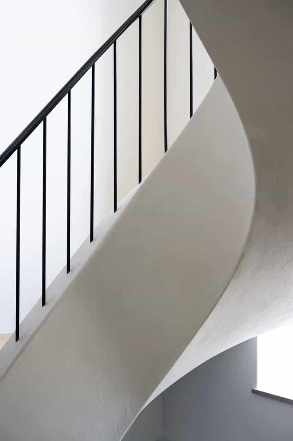 Close-up of sculptural curved staircase with black iron spindles