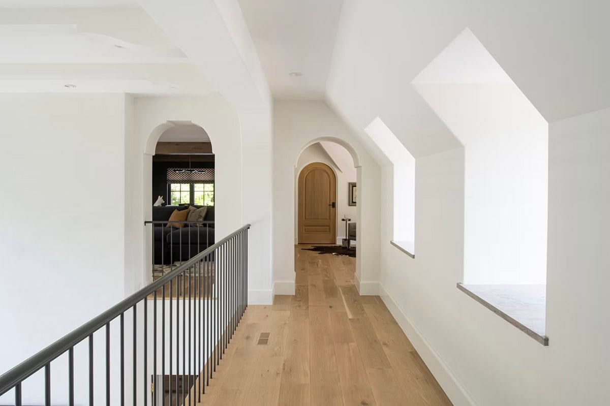 Upstairs hallway with dormer windows and arched wood door