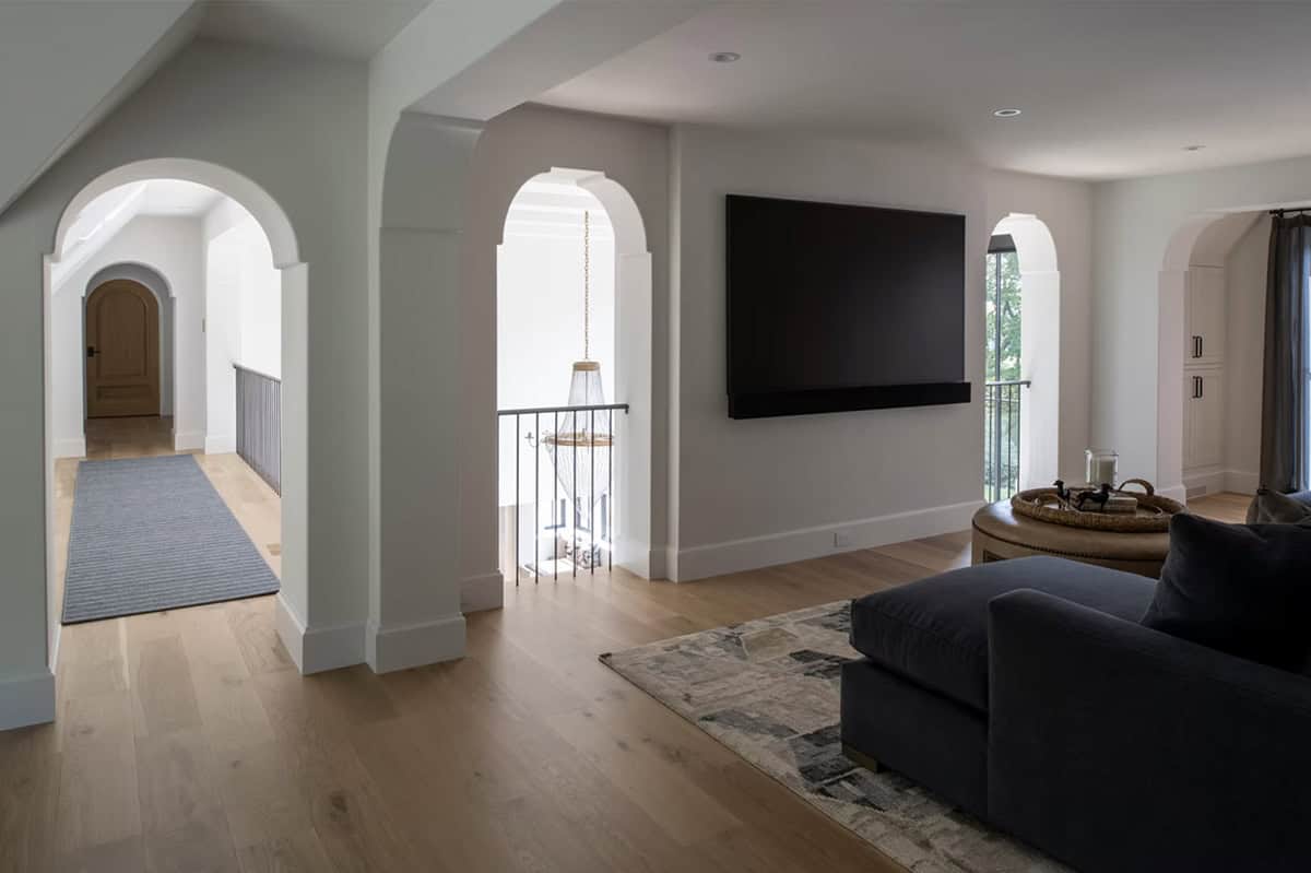 Bonus room seating area with mounted television and arched openings