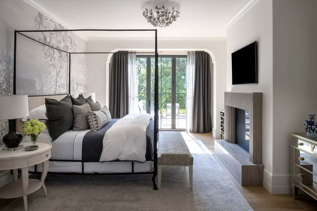 Primary bedroom with canopy bed and ribbed fireplace surround