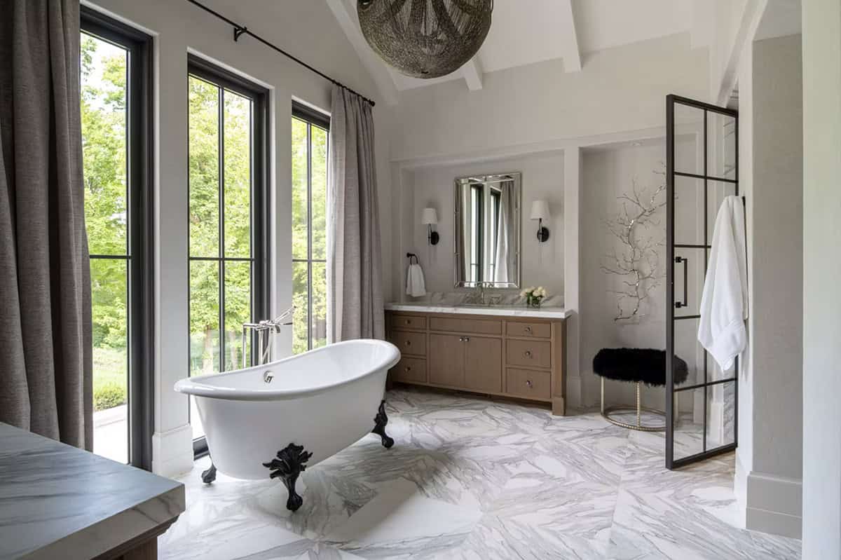Primary bathroom with clawfoot tub and marble herringbone floors