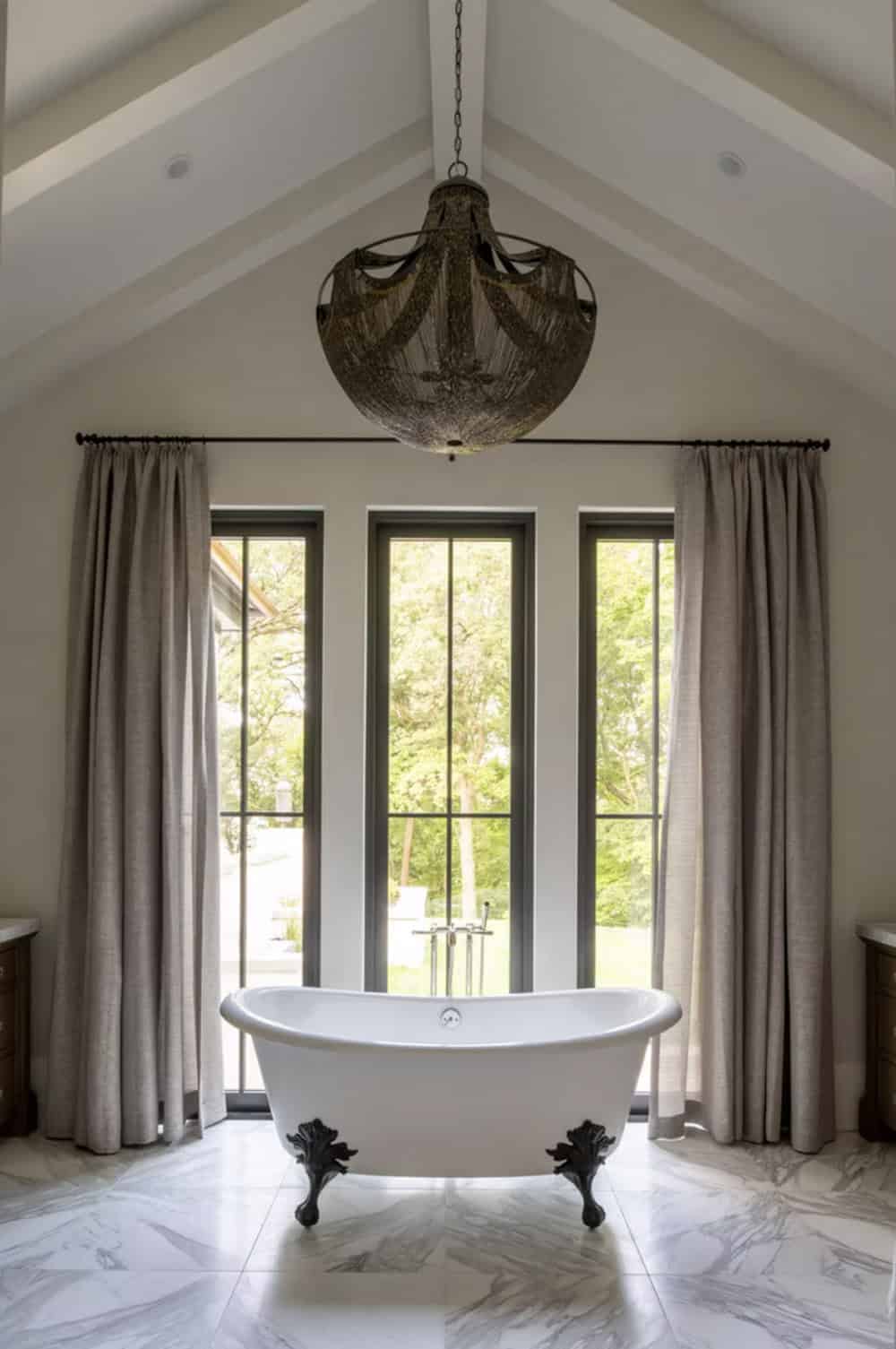 Vaulted bathroom nook with woven chandelier over clawfoot tub
