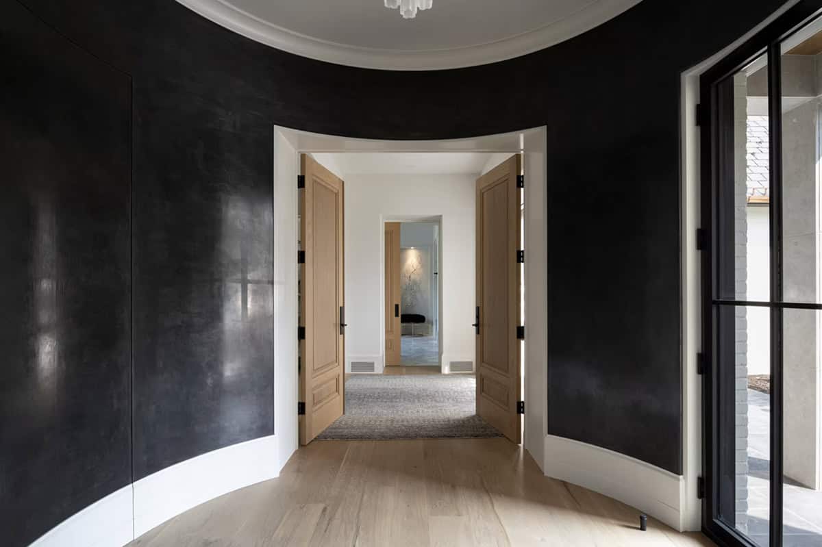 Curved dark hallway leading through double oak doors beyond