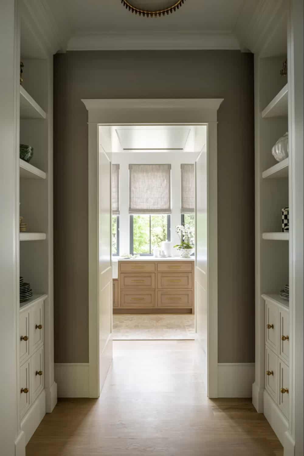 Built-in storage hallway with brass hardware leading to laundry