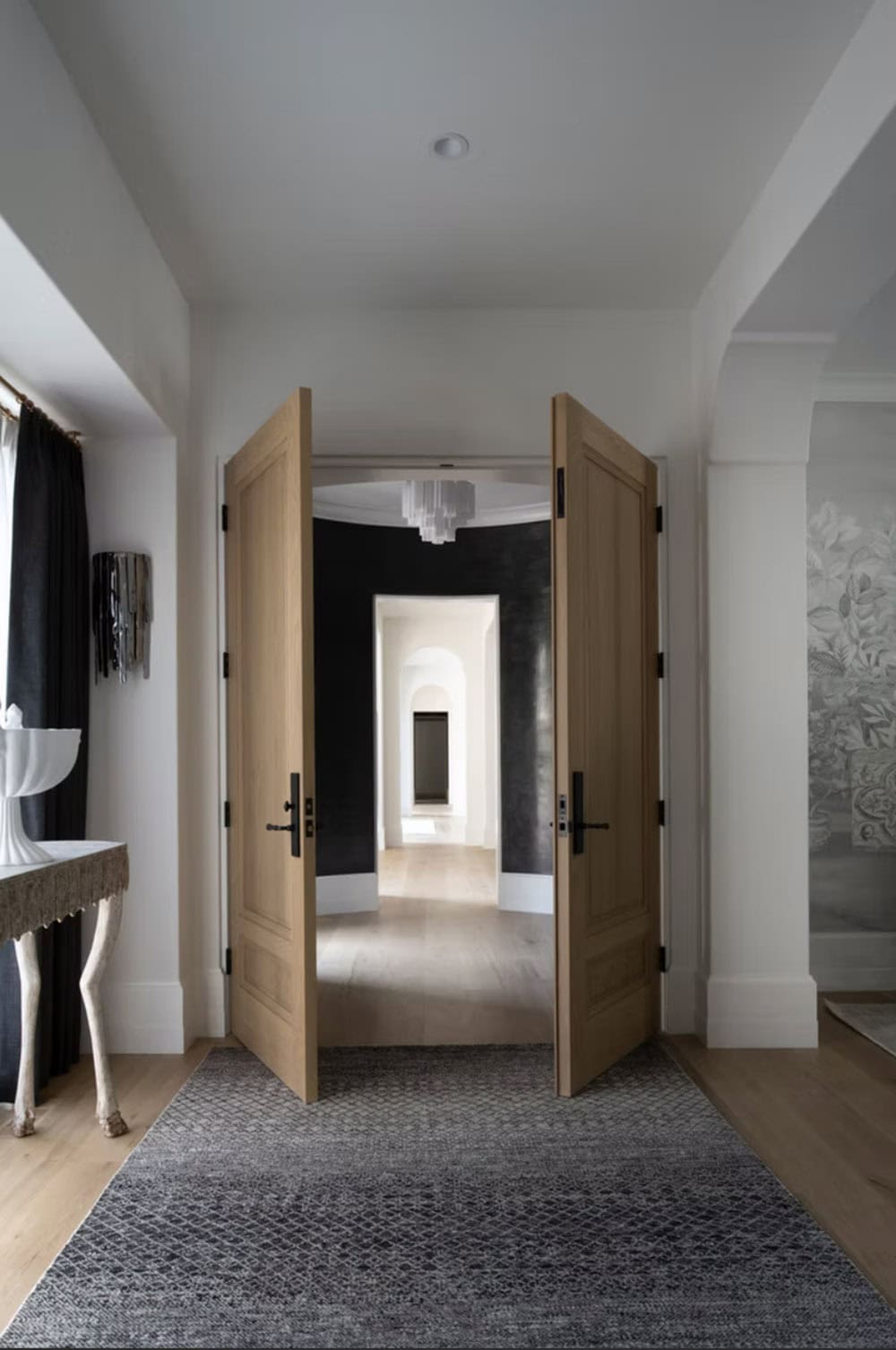 Oak double doors opening into curved black lacquered hallway