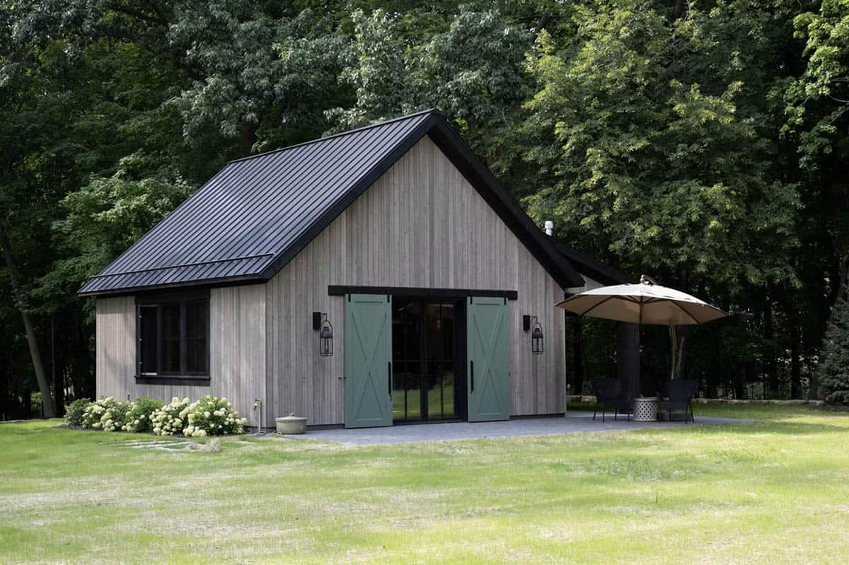 Barn-style outdoor structure with green sliding doors and black roof