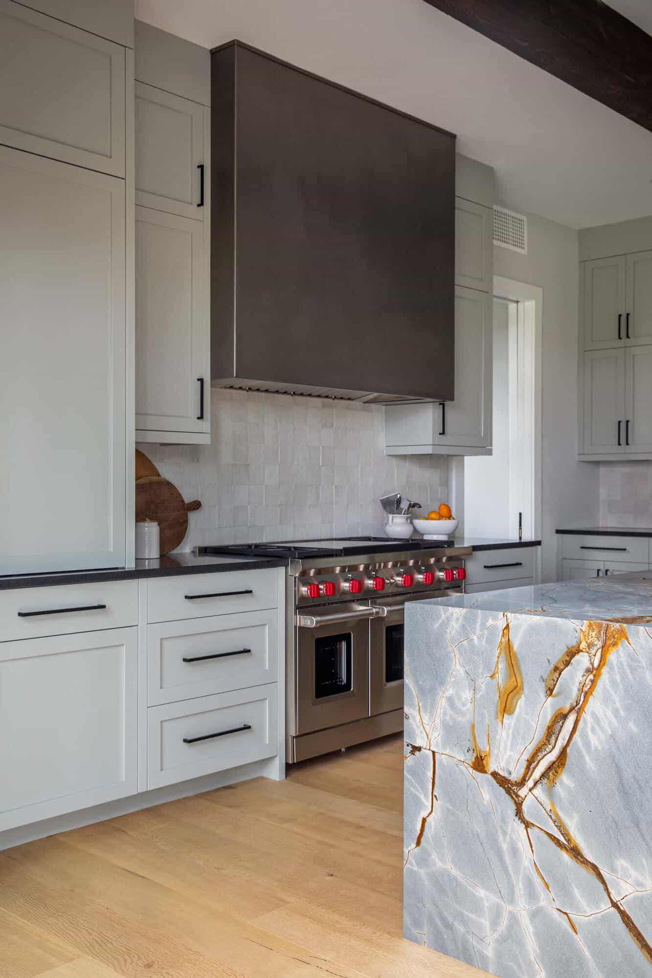 Kitchen range with red knobs beside a marble waterfall island
