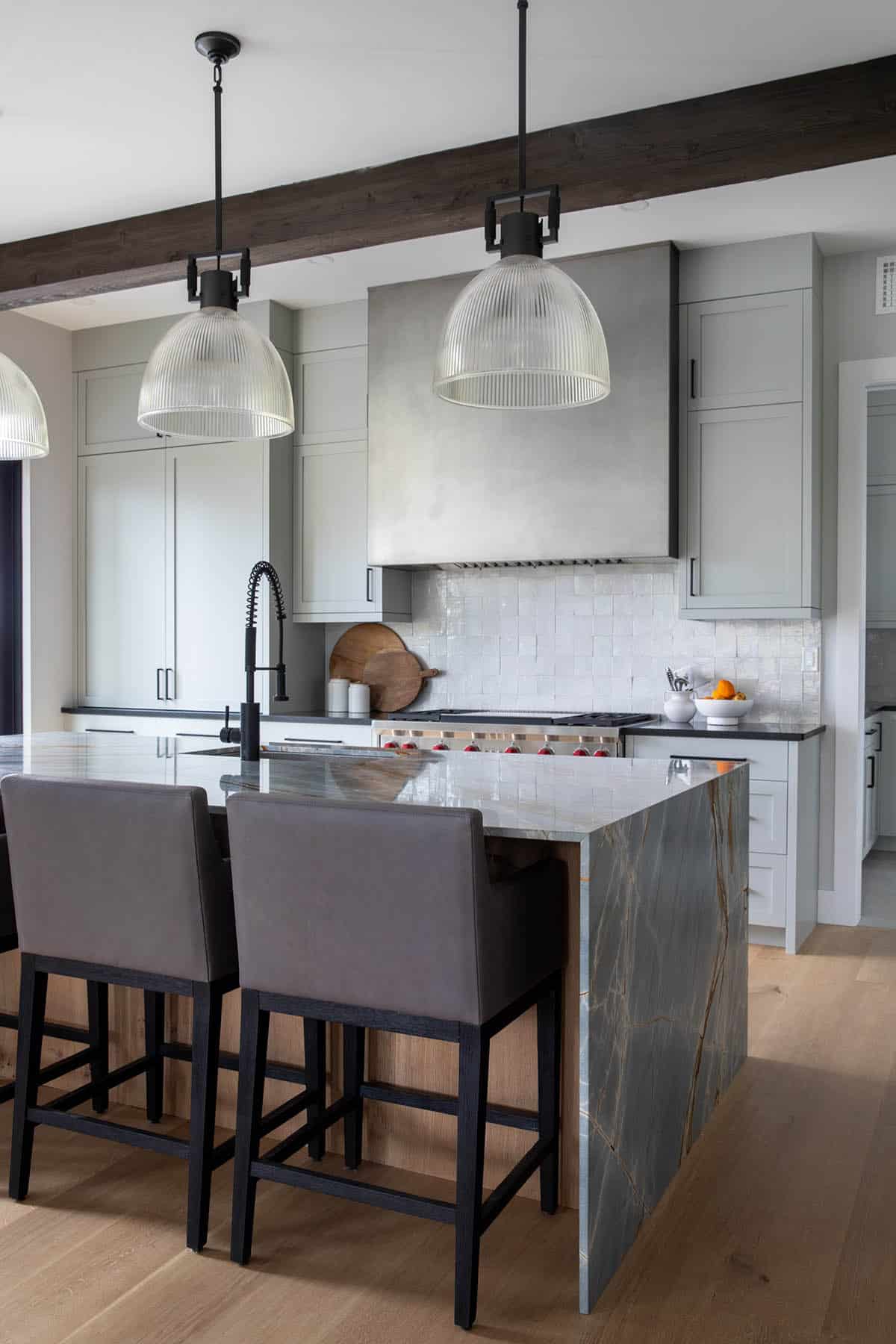 Kitchen island with leather counter stools and glass pendant lights
